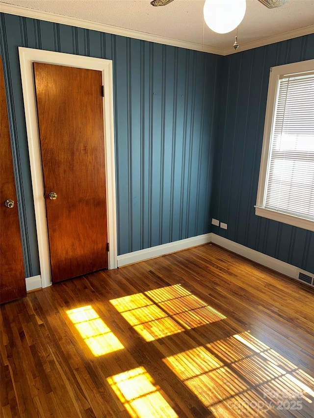 empty room with hardwood / wood-style flooring, ceiling fan, crown molding, and a textured ceiling