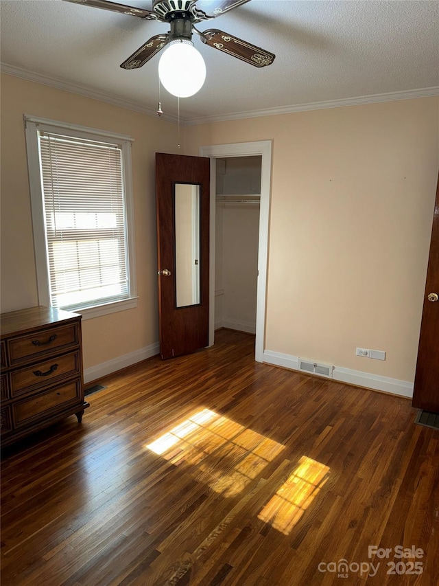 unfurnished bedroom with dark hardwood / wood-style flooring, a closet, ceiling fan, and crown molding