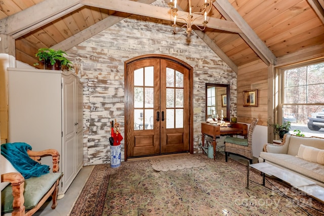 foyer entrance with a chandelier, french doors, lofted ceiling with beams, and wooden ceiling