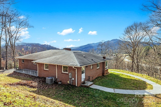 view of property exterior with a mountain view, cooling unit, and a yard