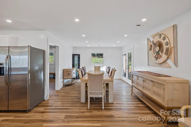 dining space with hardwood / wood-style floors, a wealth of natural light, and french doors