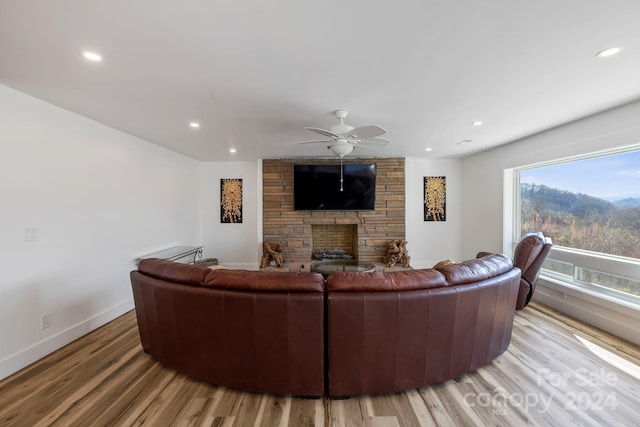 living room with hardwood / wood-style floors, a stone fireplace, and ceiling fan