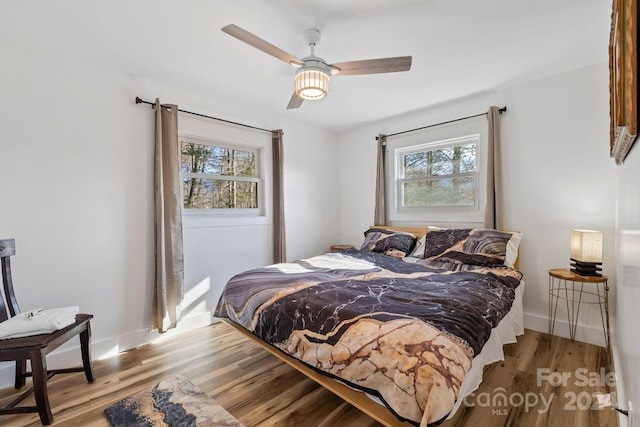 bedroom with light wood-type flooring, multiple windows, and ceiling fan