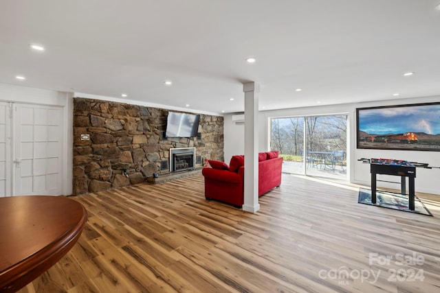 living room featuring a fireplace, light hardwood / wood-style flooring, and an AC wall unit