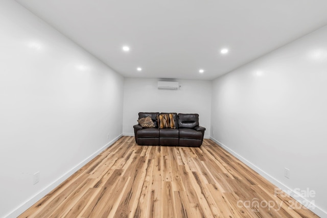 sitting room with a wall mounted air conditioner and light hardwood / wood-style flooring