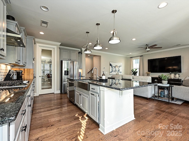 kitchen featuring gray cabinetry, sink, a kitchen island with sink, and a breakfast bar area