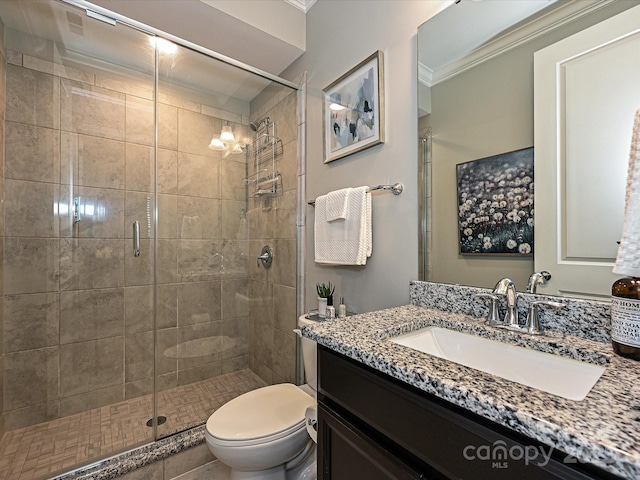 bathroom featuring vanity, toilet, a shower with shower door, and crown molding