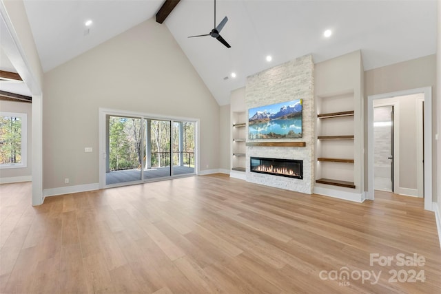 unfurnished living room featuring high vaulted ceiling, a fireplace, a wealth of natural light, and light hardwood / wood-style flooring