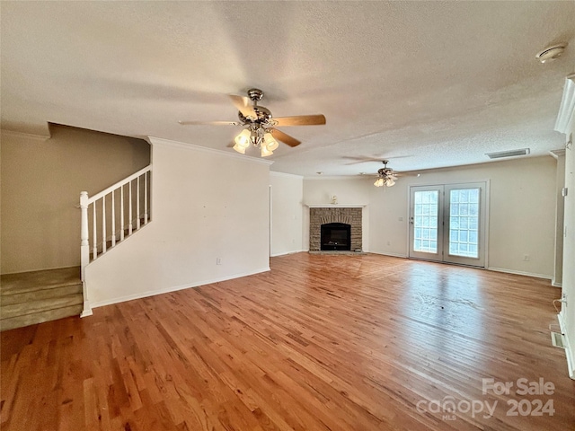 unfurnished living room featuring a fireplace, ceiling fan, light wood-type flooring, and a textured ceiling