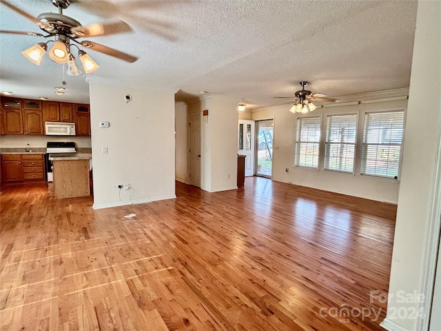 unfurnished living room featuring ceiling fan, light hardwood / wood-style flooring, a textured ceiling, and ornamental molding