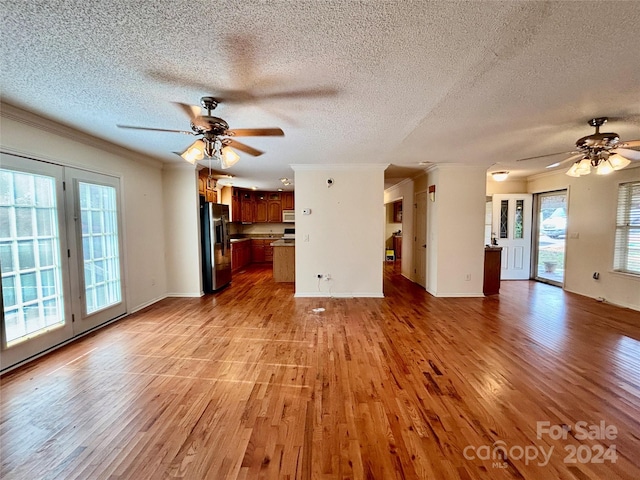 unfurnished living room with ceiling fan, light hardwood / wood-style floors, and a textured ceiling