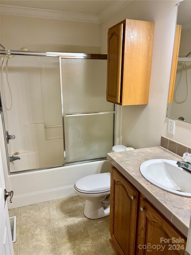 full bathroom with vanity, crown molding, enclosed tub / shower combo, tile patterned flooring, and toilet