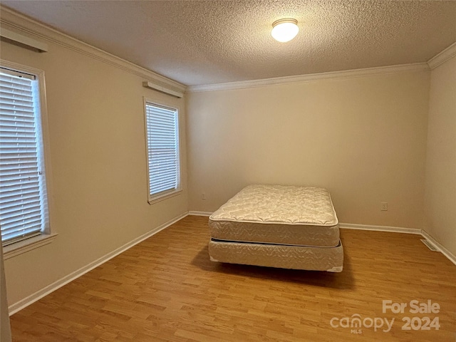 bedroom with hardwood / wood-style floors, ornamental molding, and a textured ceiling