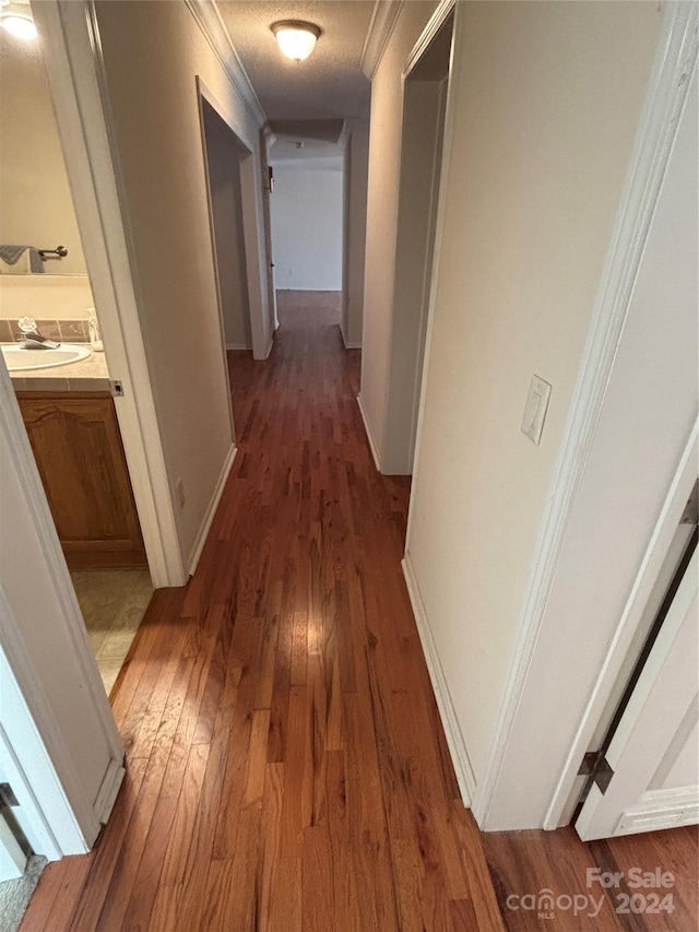 hall featuring dark hardwood / wood-style floors, sink, a textured ceiling, and crown molding