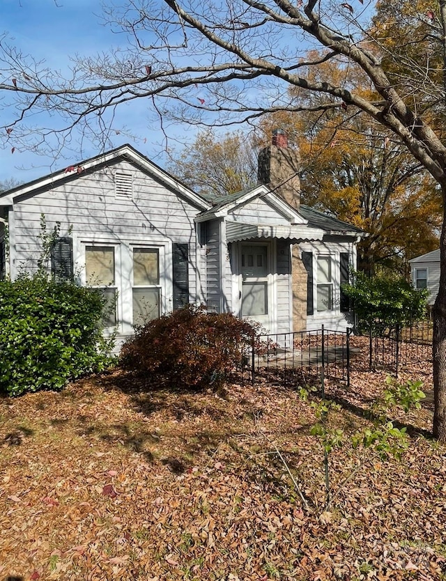 view of front facade with a fenced front yard and a chimney