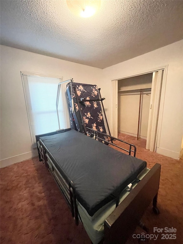 bedroom featuring a textured ceiling, carpet floors, a closet, and baseboards