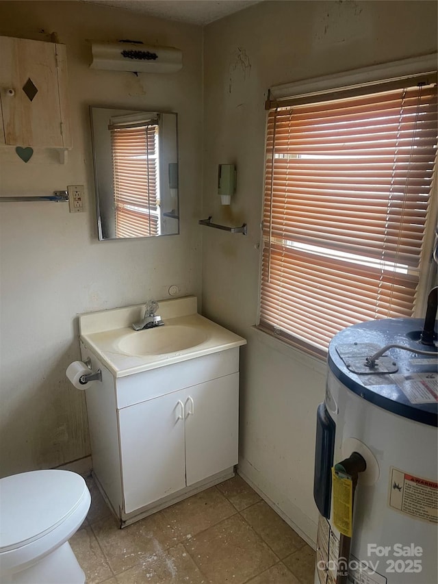 half bath featuring baseboards, water heater, vanity, and toilet