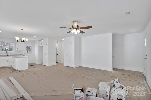 unfurnished living room featuring ceiling fan with notable chandelier and sink