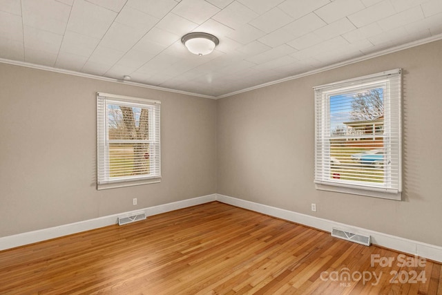 empty room featuring wood-type flooring and crown molding