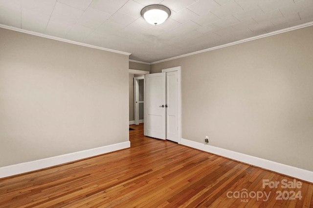 empty room with hardwood / wood-style flooring and ornamental molding