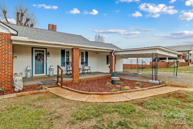 view of front of house with a carport, covered porch, and a front yard