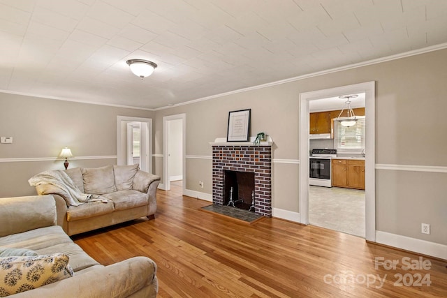 living room with hardwood / wood-style flooring, a brick fireplace, a wealth of natural light, and crown molding