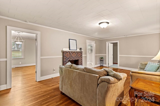 living room with hardwood / wood-style flooring, ornamental molding, and a brick fireplace