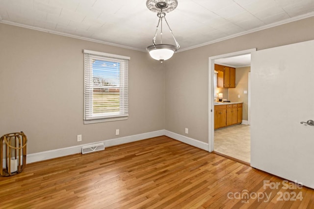 spare room featuring crown molding and light wood-type flooring