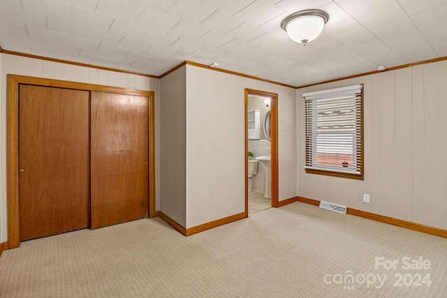 unfurnished bedroom featuring light carpet, ensuite bathroom, a closet, and crown molding