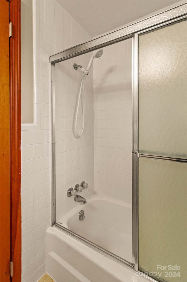 bathroom featuring combined bath / shower with glass door and tile walls