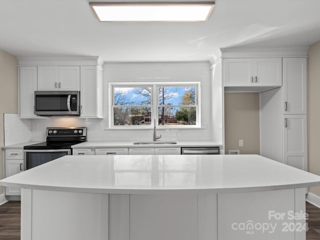 kitchen featuring a center island, white cabinets, sink, dark hardwood / wood-style floors, and appliances with stainless steel finishes