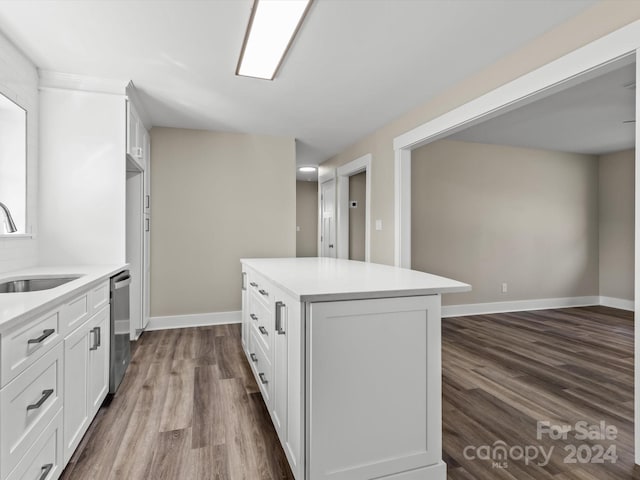 kitchen featuring white cabinets, sink, stainless steel dishwasher, dark hardwood / wood-style floors, and a kitchen island