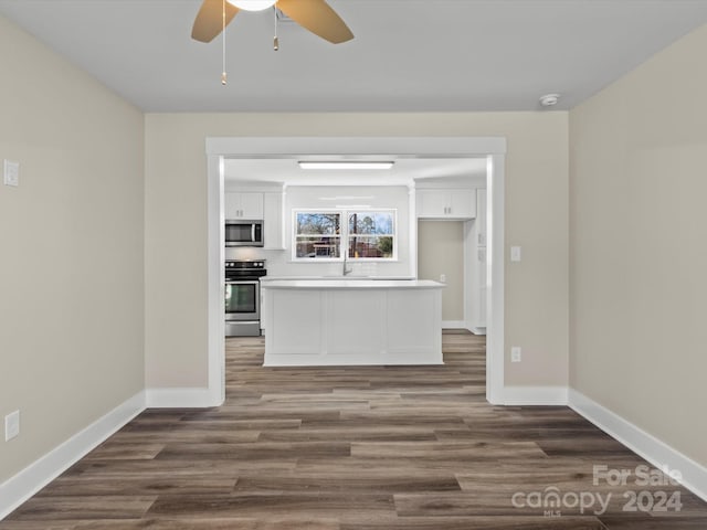 unfurnished living room featuring ceiling fan and dark wood-type flooring