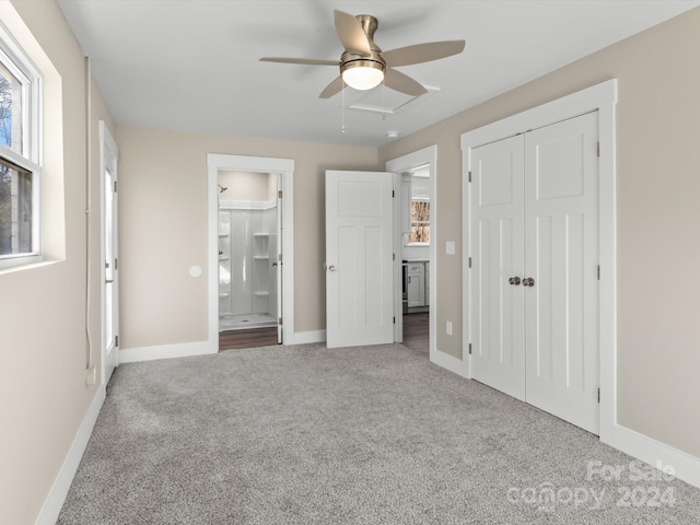 unfurnished bedroom featuring carpet flooring, a closet, ensuite bathroom, and ceiling fan