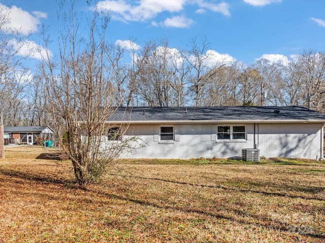 back of property featuring central AC, an outdoor structure, and a lawn