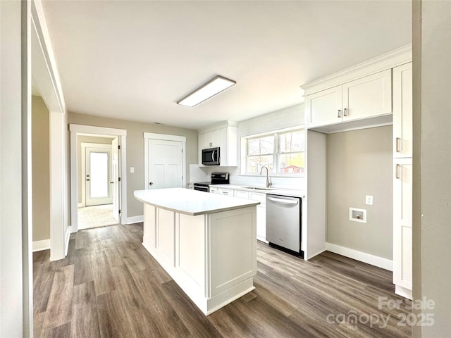 kitchen with stainless steel appliances, white cabinetry, a center island, and hardwood / wood-style floors