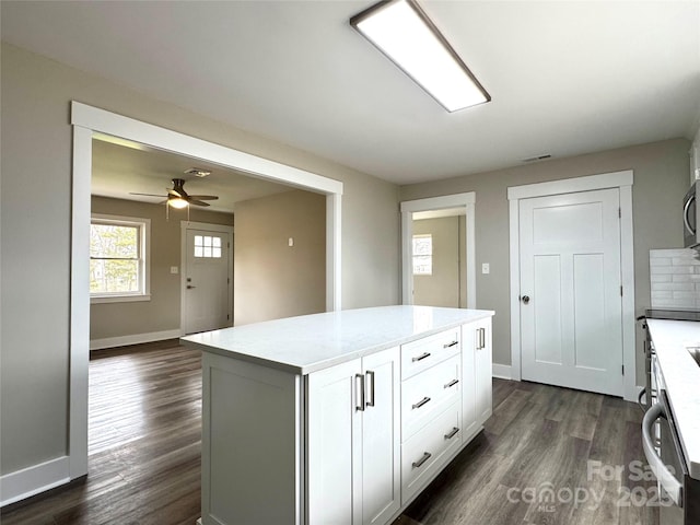 kitchen with dark hardwood / wood-style floors, dishwasher, white cabinets, a center island, and ceiling fan