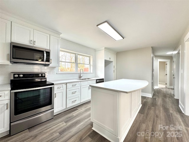 kitchen with sink, hardwood / wood-style flooring, white cabinets, and appliances with stainless steel finishes