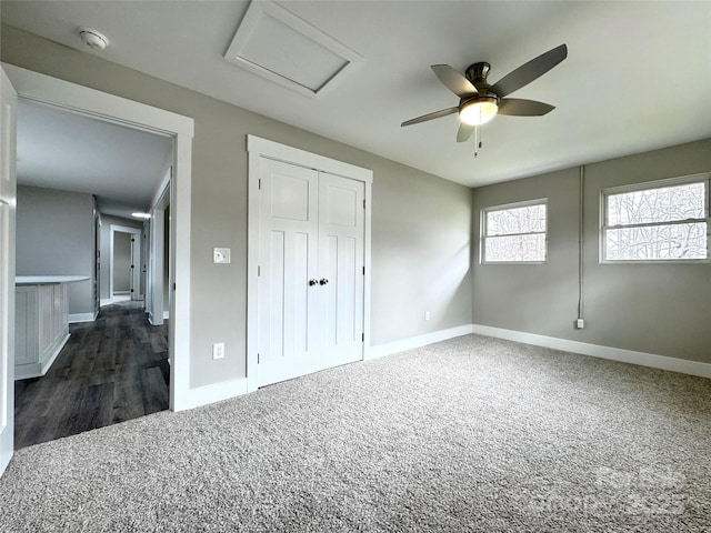 unfurnished bedroom with dark colored carpet, ceiling fan, and a closet