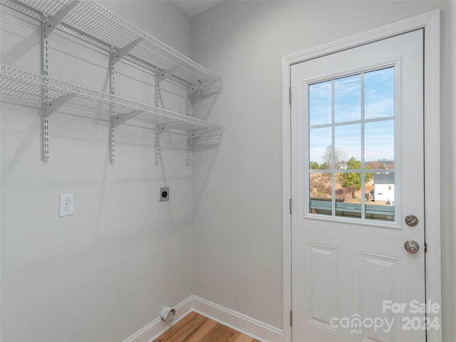 clothes washing area with a wealth of natural light, hardwood / wood-style floors, and hookup for an electric dryer