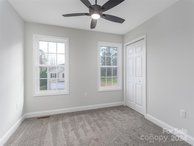 unfurnished room with carpet floors, a wealth of natural light, and ceiling fan