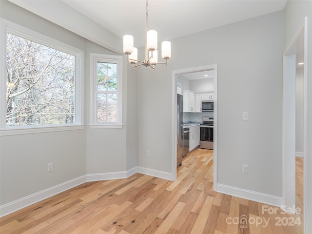 unfurnished dining area featuring light hardwood / wood-style floors and a notable chandelier