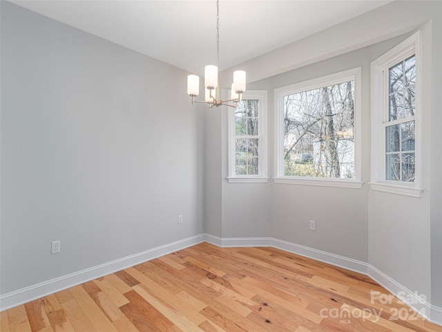 empty room featuring wood-type flooring and an inviting chandelier