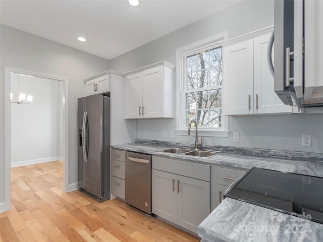 kitchen featuring stainless steel appliances, sink, decorative light fixtures, white cabinets, and light hardwood / wood-style floors