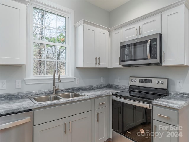 kitchen featuring white cabinets, light stone counters, sink, and stainless steel appliances