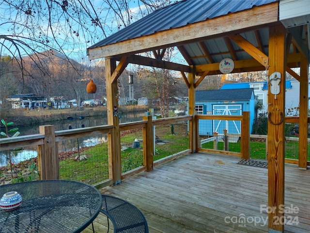 wooden deck featuring a water view and an outdoor structure