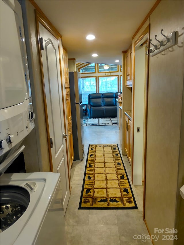 laundry area with stacked washer / dryer and light tile patterned flooring