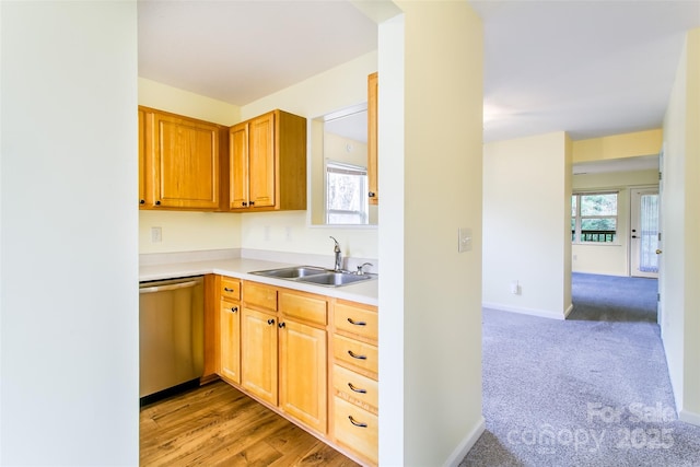 kitchen featuring light colored carpet, light countertops, a sink, dishwasher, and baseboards