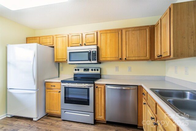 kitchen featuring a sink, stainless steel appliances, dark wood-style flooring, and light countertops