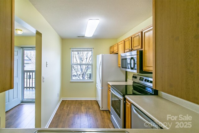 kitchen featuring stainless steel appliances, brown cabinets, a healthy amount of sunlight, and visible vents